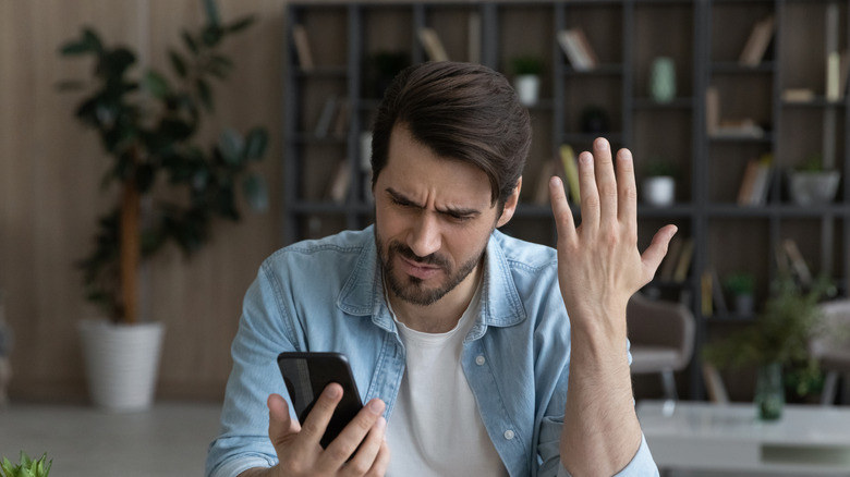 man frustrated looking at smartphone