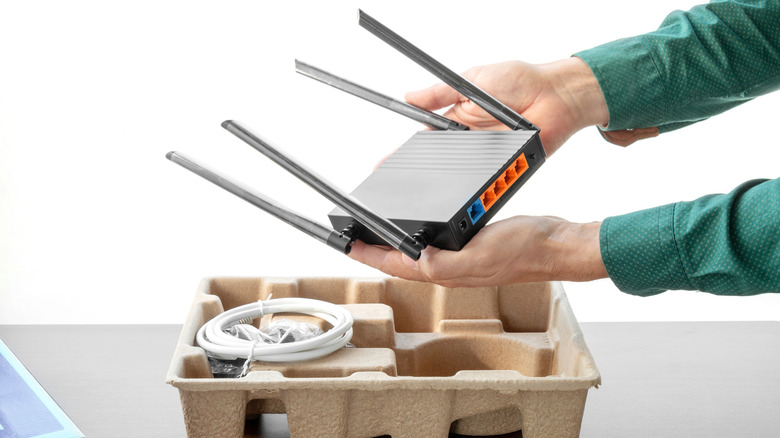 Someone removing a new Wi-Fi router with antennas from its original packaging