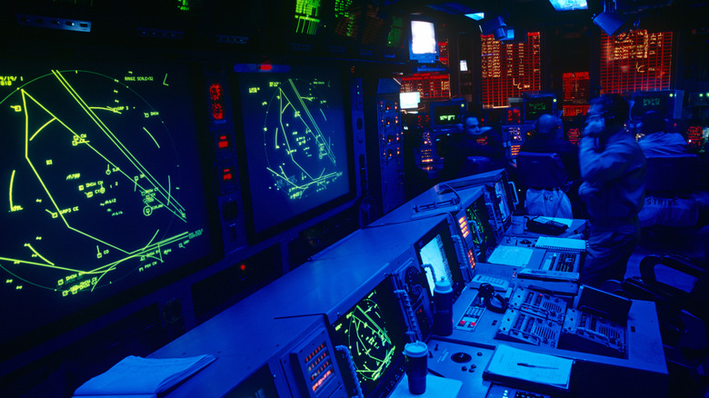 U.S Navy personnel in aircraft carrier information nerve center with radar screens