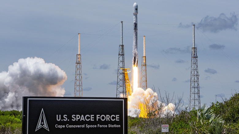 A white Falcon 9 rocket takes off on its GPS III mission, during a clear day at U.S. Space Force base Cape Canaveral.
