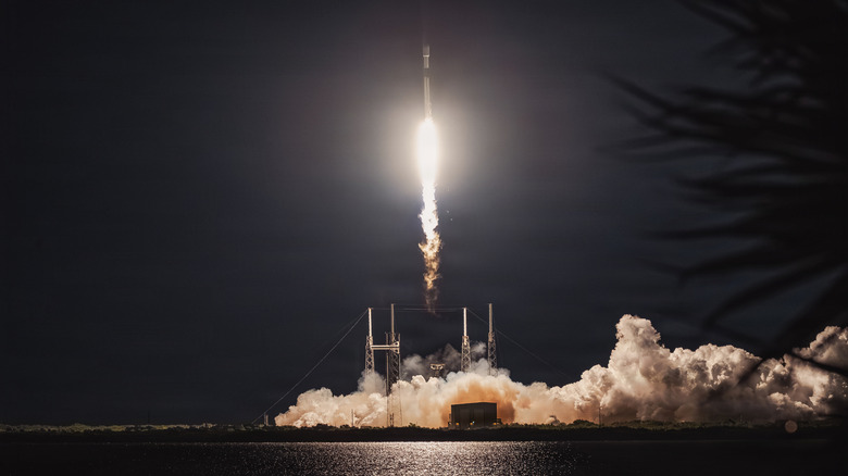 A SpaceX Falcon 9 rocket carrying a GPS III mission launches over the waters of Cape Canaveral against a dark night sky on January 2026.