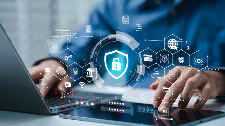 person using laptop and tablet with concept security icons floating above.