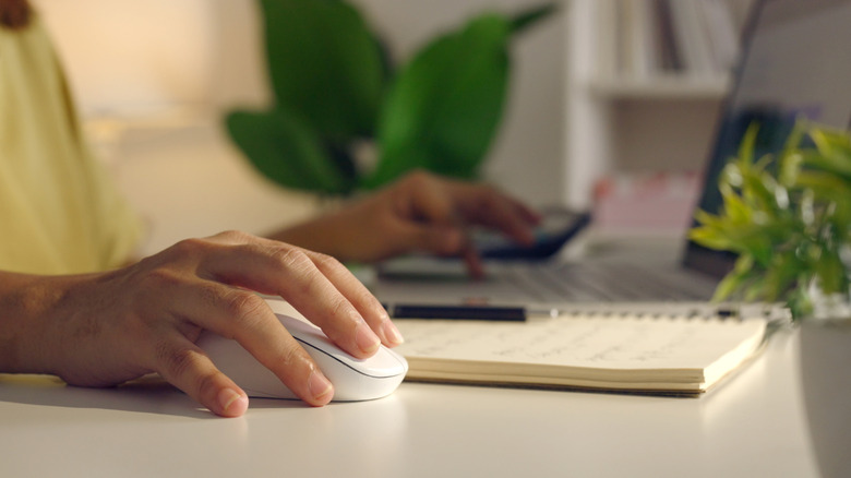 Visually frustrated woman using a computer mouse with her laptop.
