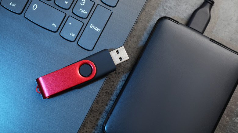 A USB flash and external hard drive placed next to a laptop