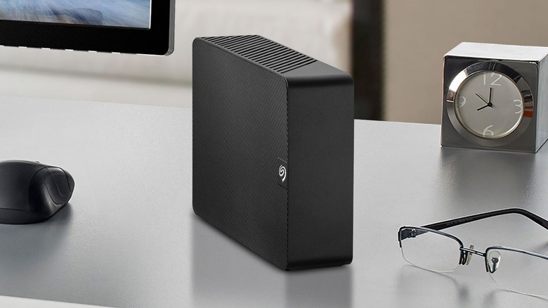 Seagate Expansion Hard Drive placed on a desk next to a clock and a pair of glasses