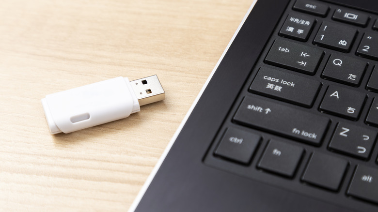White USB stick next to a laptop.