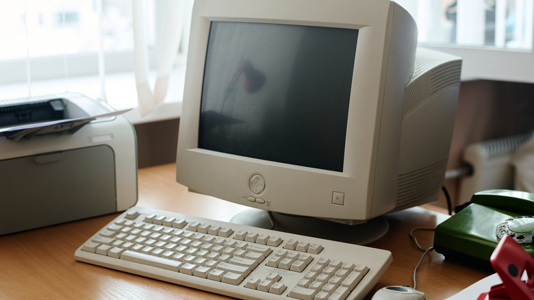 An old PC setup, including a CRT monitor, mechanical keyboard, and wired mouse.