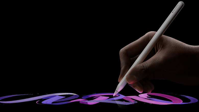 Close up of a hand against a black background drawing with an Apple Pencil Pro