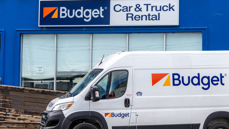 A Budget Car & Truck Rental location with a rental van under the Budget sign with the orange logo behind