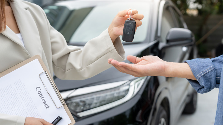Dealership manager handing car keys to the new owner