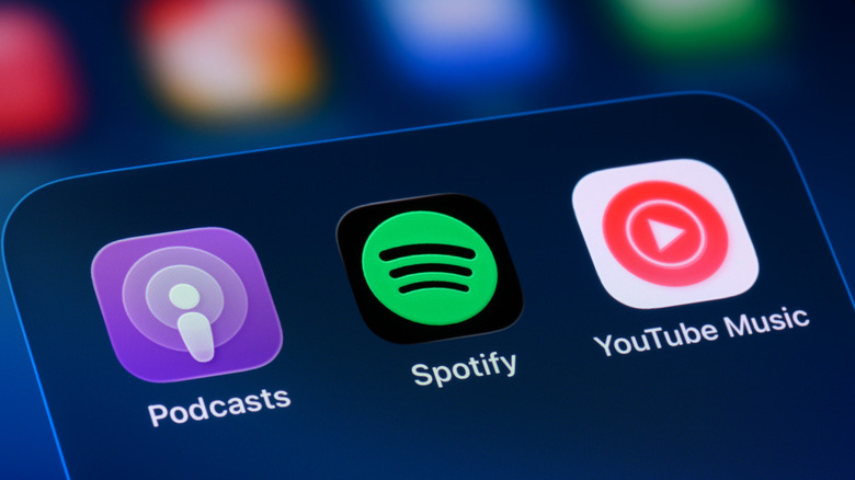 YouTube Music app next to the Spotify and Podcasts apps displayed on a smartphone home screen