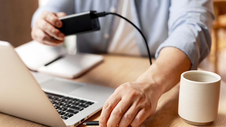 An office worker connecting an external drive to laptop