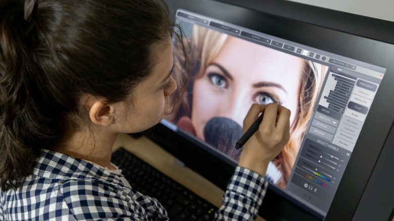 A young woman using Photoshop on a large tablet screen