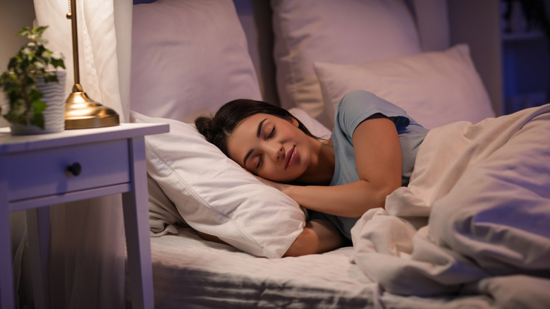 person sleeping in bed with lamp on