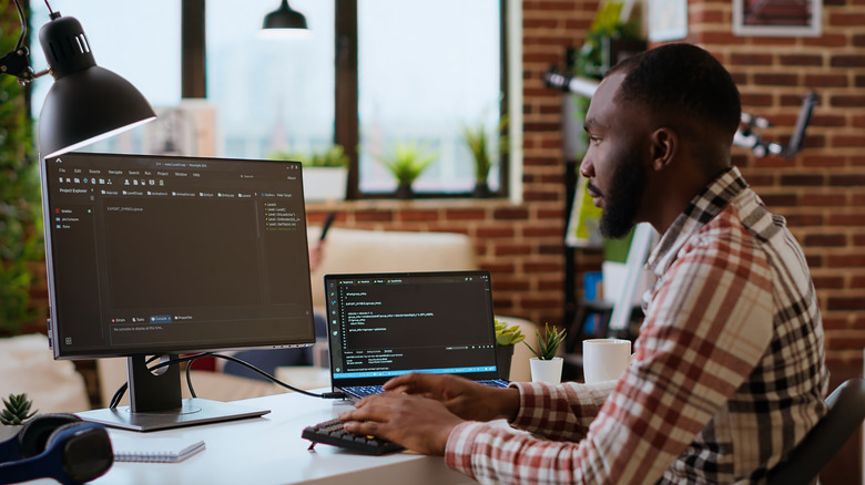 A man working at a desk with a laptop and another monitor spaced apart