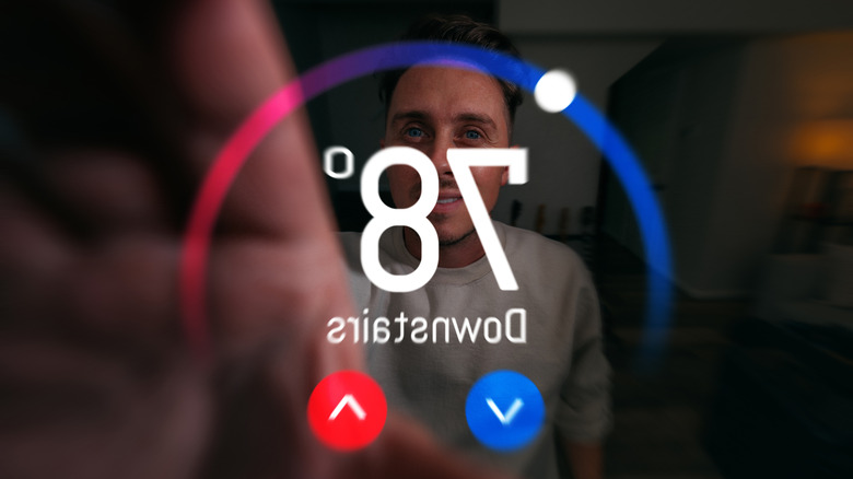 a man's reflection in a smart thermostat that reads 78