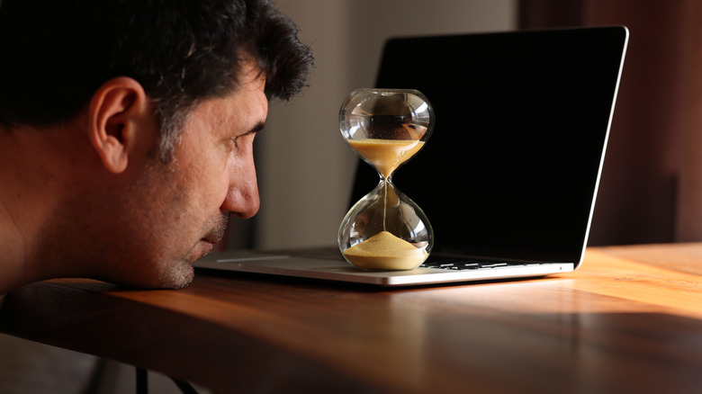 a man watching sand in an hourglass, concept of waiting