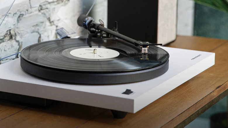 A Crosley turntable with a white plinth playing a vinyl record