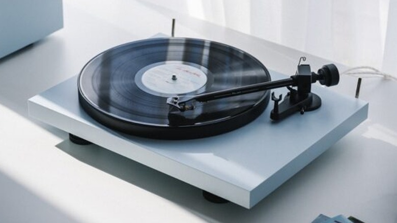 A Pro-Ject turntable playing a vinyl record on a white surface