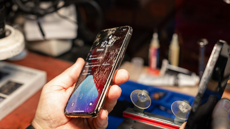 smartphone repair tech inspecting iPhone with cracked screen