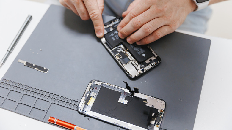 person works on repairing iPhone display and battery
