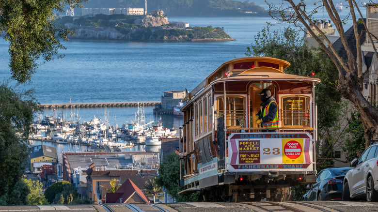 A San Francisco cable car heading down a hill as it overlooks the bay