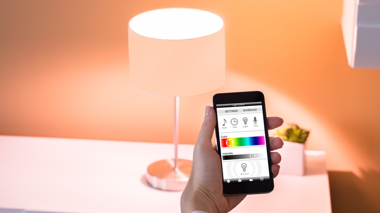 A person controlling a smart table light with a phone