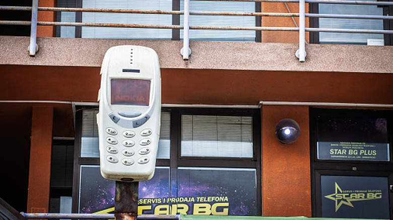 Nokia 3310 phone replica mounted on a pole outside a phone repair and sales shop
