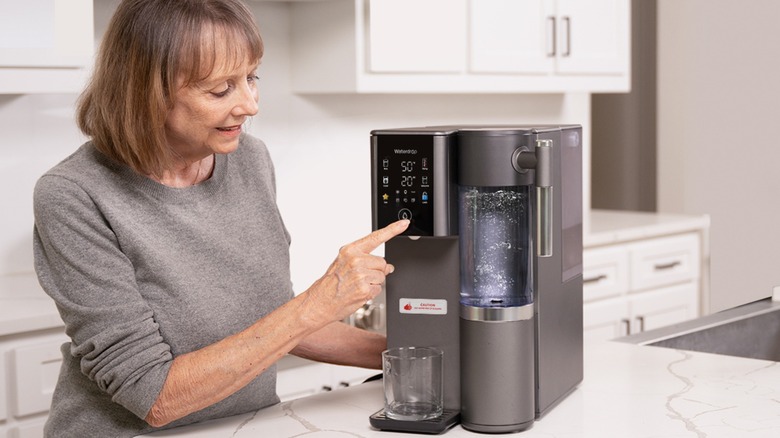 Woman using touch screen on Waterdrop Filter's A2 Countertop RO System
