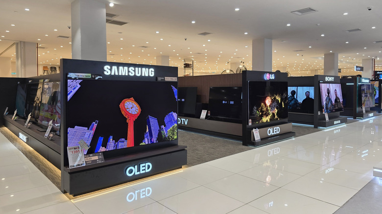 A row of OLED television displays from Samsung, LG, and Sony inside a large electronics store