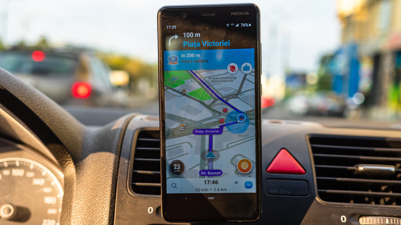 Waze used inside a car, with a police incident report appearing on the map along the route of travel.