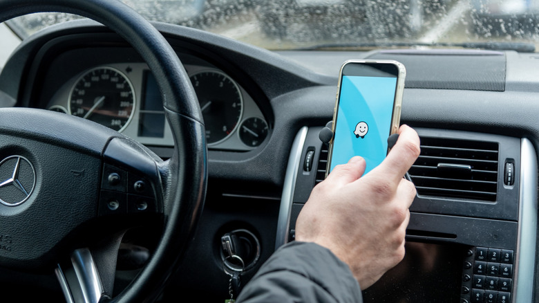 A driver using the Waze app on a smartphone.