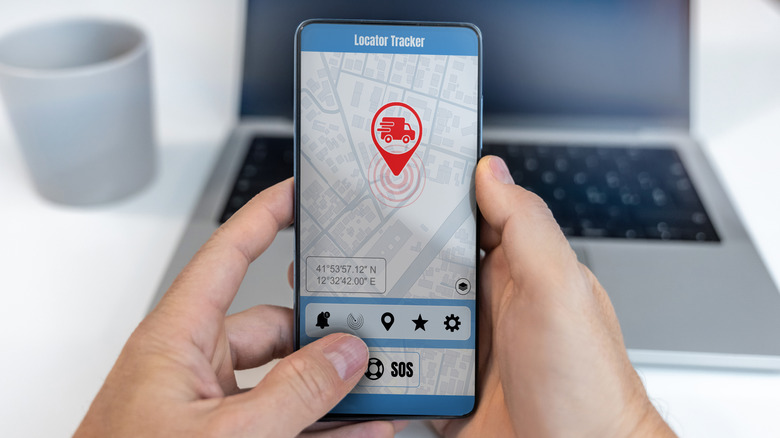 A person holding a phone and tracking the location of a delivery