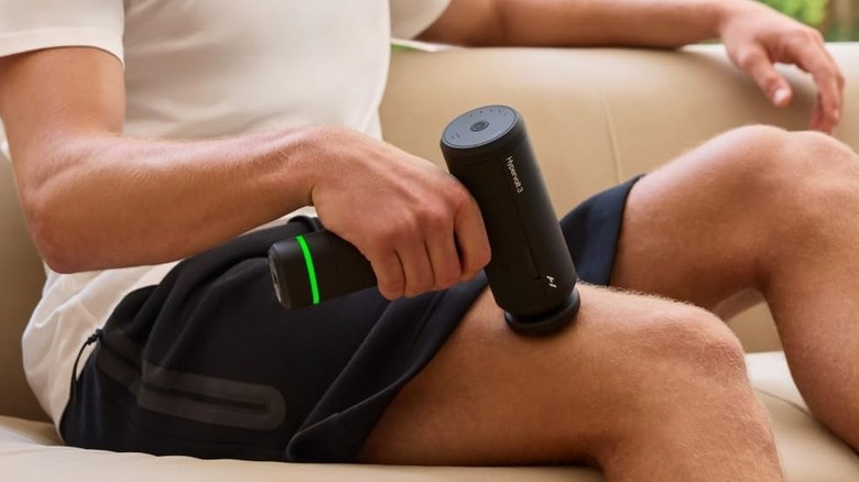 A person using the Hyperice Hypervolt 3 massage gun on their thigh.