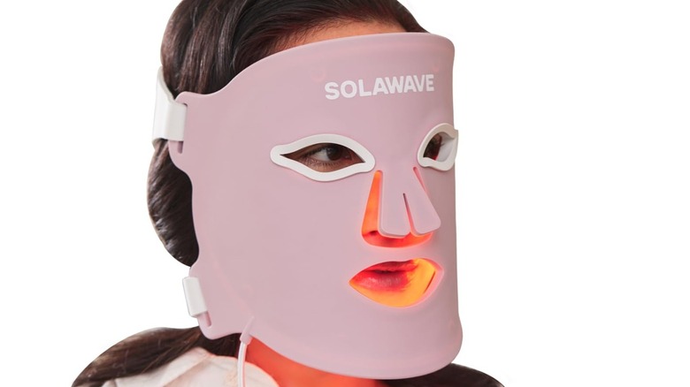 A person wearing the Solawave Wrinkle Retreat Pro light therapy face mask, on a white background.