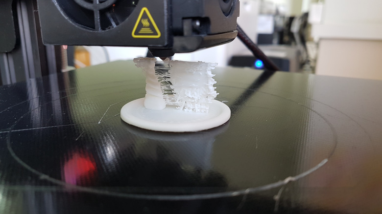 3D printer making a plastic model with a flat base like a brim.