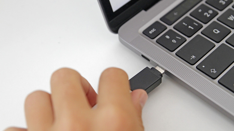 a hand plugging a USB stick into a computer
