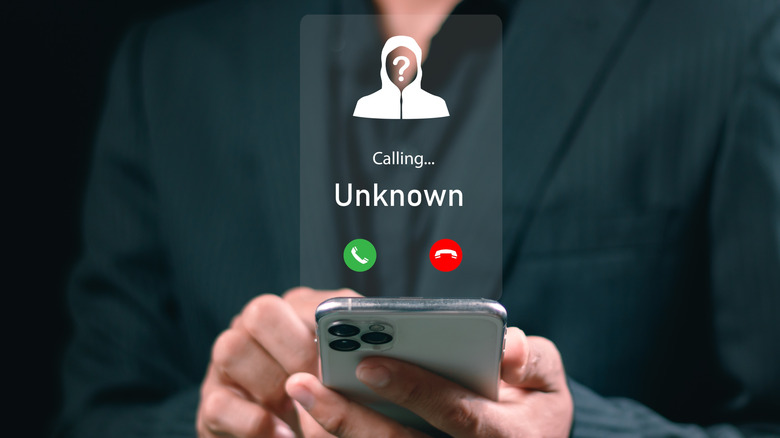 A man holding mobile phone with incoming call from unknown caller.