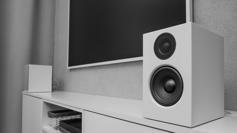 Speakers on a table with a TV on the wall