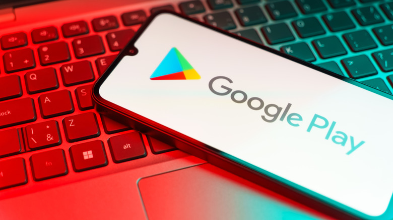 A Google Play Store logo shown on a smartphone that is placed on top of a laptop.