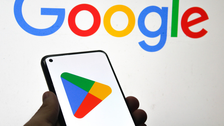 The Google Play Store logo shown on a smartphone screen. A Google logo, set against a white backdrop, is the background.