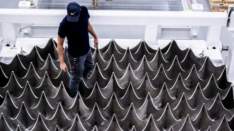 A SpaceX engineer stands on a new grid fin