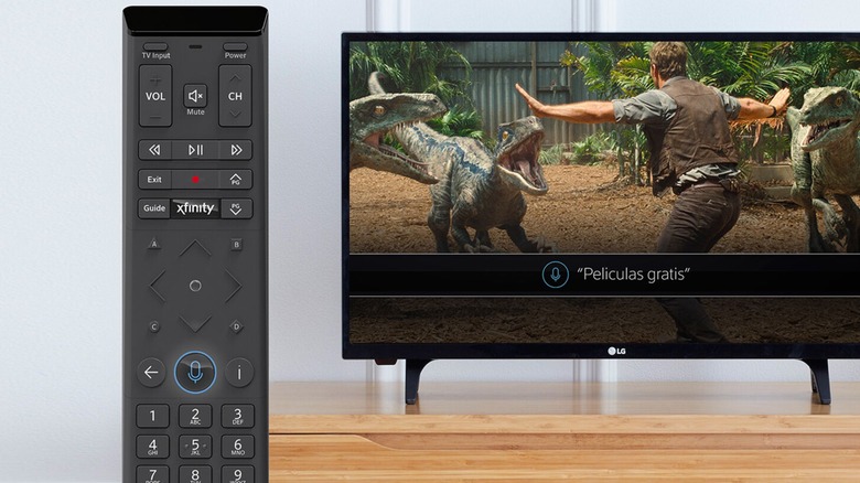 A superimposed black Xfinity voice remote stands next to a TV displaying what appears to be a scene from a dinosaur movie, possibly "Jurassic Park"