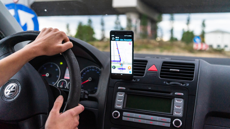 Driver with smartphone mounted using Waze to navigate traffic.