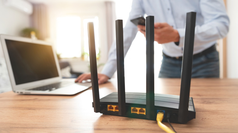 Router on a desk with a user on a phone and laptop in the background