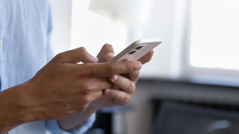 Person using a smartphone in an office-like environment.