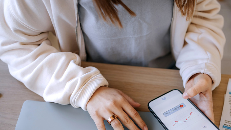 A person wearing smart ring and tracking g their health data on a smartphone