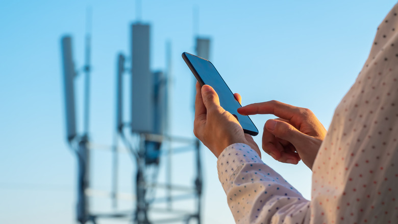 Man using a phone near a 5G tower.
