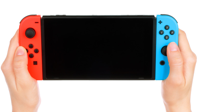 A person holding a Nintendo Switch that is powered off