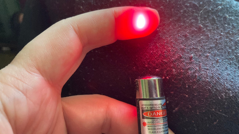 Someone shining a red laser pointer on their index finger.